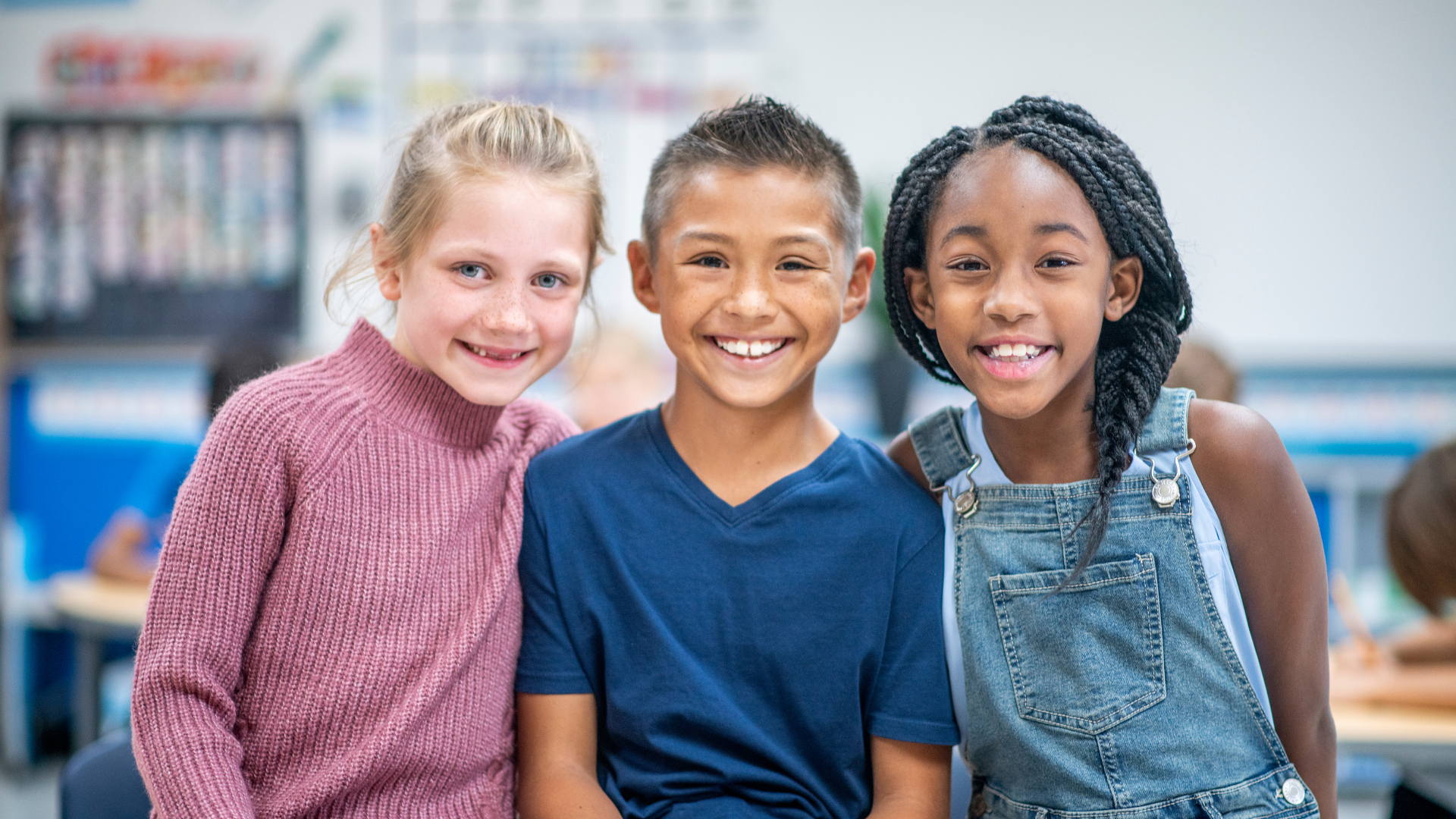 Diverse k-12 students pose for a picture while in their classroom